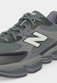 Γκρι και μαύρο παπούτσι τρεξίματος New Balance 2000 με άνω μέρος από δίχτυ, μαλακή σόλα και μεγάλο λευκό λογότυπο "N" στην πλευρά.