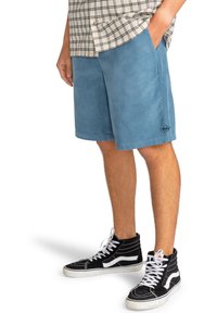 Shorts in corduroy blu con tasche laterali, che arrivano a metà coscia, abbinati a sneakers alte nere con dettagli bianchi.