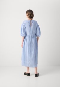 Blå og hvit stripete midi-kjole med puff-ermer, elastisk midje og nøkkelhullåpning bak. Brukt med svarte flate sko.