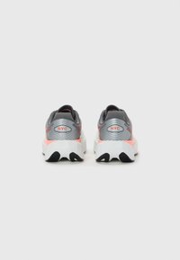 Ein Paar graue und wei�ße Laufschuhe mit korallfarbenen Akzenten, von hinten gesehen, mit "NYC"-Text auf den Fersenschlaufen.