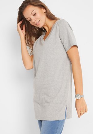 T-shirt grigio a maniche corte con scollatura a V e fessure laterali, realizzato in tessuto morbido. Abbinato a un orologio grigio, indossato con jeans blu.