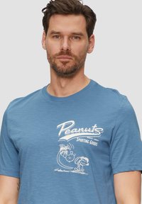 Niebieska bawełniana koszulka z okrągłym dekoltem, krótkimi rękawami i luźnym krojem, z białym wzorem graficznym z tekstem "Peanuts" oraz postaciami z kreskówek.