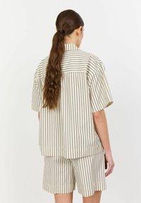 Short-sleeved shirt and shorts set in cream with thin vertical brown stripes. Soft fabric with a relaxed fit and minimalistic design.