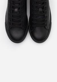 Baskets en cuir noir à surface lisse, bout arrondi et lacets plats. Présentent un design simple avec une couture discrète et une semelle en caoutchouc.