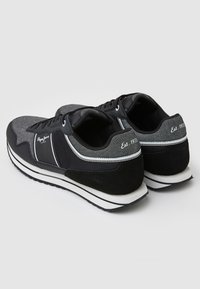 Black and gray sporty sneakers featuring a mix of textured materials, including suede and mesh, with white accents and a cushioned sole.