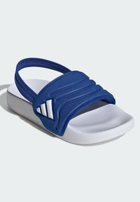 Modri umetni natikač s širokim teksturiranim trakom in belim podplatom iz EVA materiala. Na traku so tri bele poudarjene črte za dodatne podrobnosti.