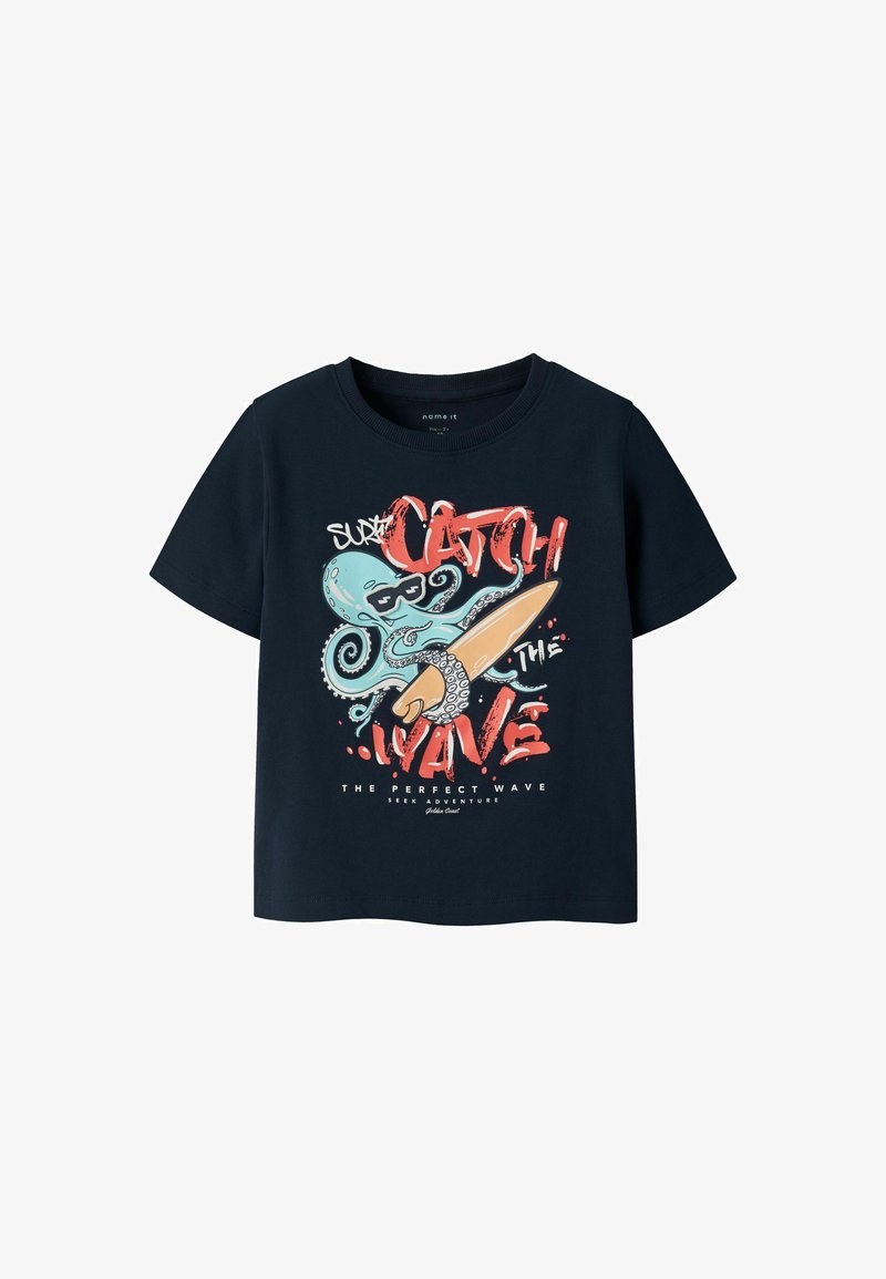 Chemise bleu marine à manches courtes avec un graphisme d'une pieuvre turquoise portant des lunettes de soleil, tenant une planche de surf, accompagnée du texte "Attrape la vague."