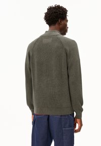 Dunkelgrüner Strickpullover mit gerippter Textur, mit hohem Kragen und Raglanärmeln, von hinten präsentiert, mit sichtbaren Nähdetails.