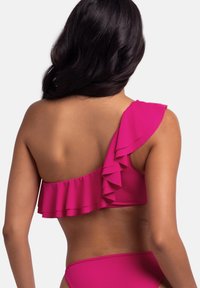 Asimetriska rozā bikini augšdaļa ar vienu kraukšķīgu siksniņu un gludu muguru, izgatavota no elastīga materiāla, lai nodrošinātu komfortu un atbilstību.