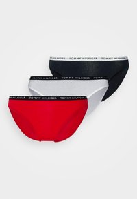 Three pairs of cotton briefs in red, white, and navy, each with a black waistband featuring "TOMMY HILFIGER" in white lettering.