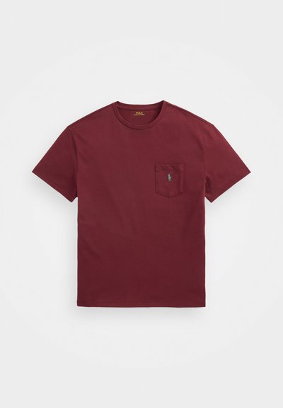 Burgundyröd bomulls t-shirt med rundad halsringning, korta ärmar och en framficka med en grön broderad logotyp. Slät yta.