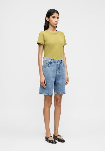 Λαδί κοντομάνικη μπλούζα με στρογγυλή λαιμόκοψη, σε συνδυασμό με ανοιχτόχρωμα τζιν σορτς με πλαϊνές τσέπες και ξεφτισμένο τελείωμα.