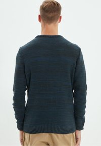 Pull en maille bleu foncé avec un motif texturé. Poignets et ourlet côtelés, col rond standard et coupe décontractée. Détails de coutures visibles.
