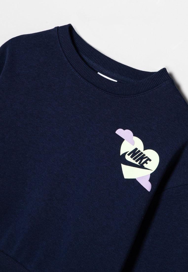 Sweatshirt bleu marine avec un col rond côtelé, arborant un logo en forme de cœur aux couleurs pastel et le texte "NIKE" en noir. Texture douce.