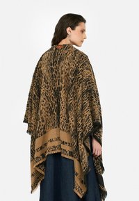 Pončo s leopardským vzorom v hnedej a čiernej farbe, s třásňami na okrajoch a voľným strihom. Vyrobené z mäkkého materiálu s hladkou textúrou.