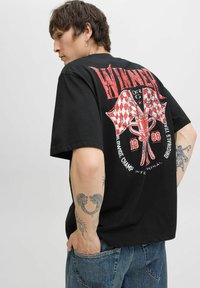 Sort bomulds T-shirt med et stort rødt grafiktryk på ryggen, som inkluderer ternede flag og et trofæ, med korte ærmer og en afslappet pasform.