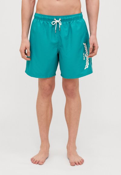 Teal svømmebukser lavet af letvægtsstof, med en elastisk talje med snor, og et hvidt logo med bladdesign på siden.