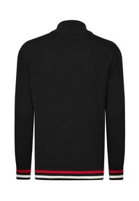 Maglione lavorato a maglia nero con un motivo testurizzato, colletto alto e dettagli a strisce rosse, bianche e nere in contrasto all'orlo e ai polsini.