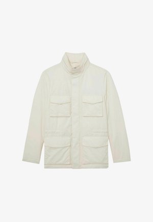 Krém színű, könnyű dzseki magas gallérral, elülső cipzárral, amelyet takaró fedél takar, és négy takarós zsebbel az elülső oldalon.