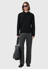 Mustapaita neulepolo, harmaat leveälahkeiset farkut, mustat aurinkolasit ja teksturoitu musta laukku, yhdistettynä mustiin kenkiin. Yksinkertainen ja moderni muotoilu.