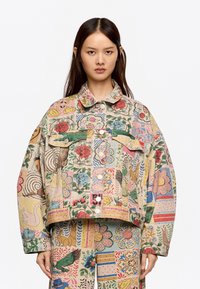 Chaqueta de mezclilla de gran tamaño y multicolor con patrones florales y de animales, dos bolsillos en el pecho y cierre de botón a presión.