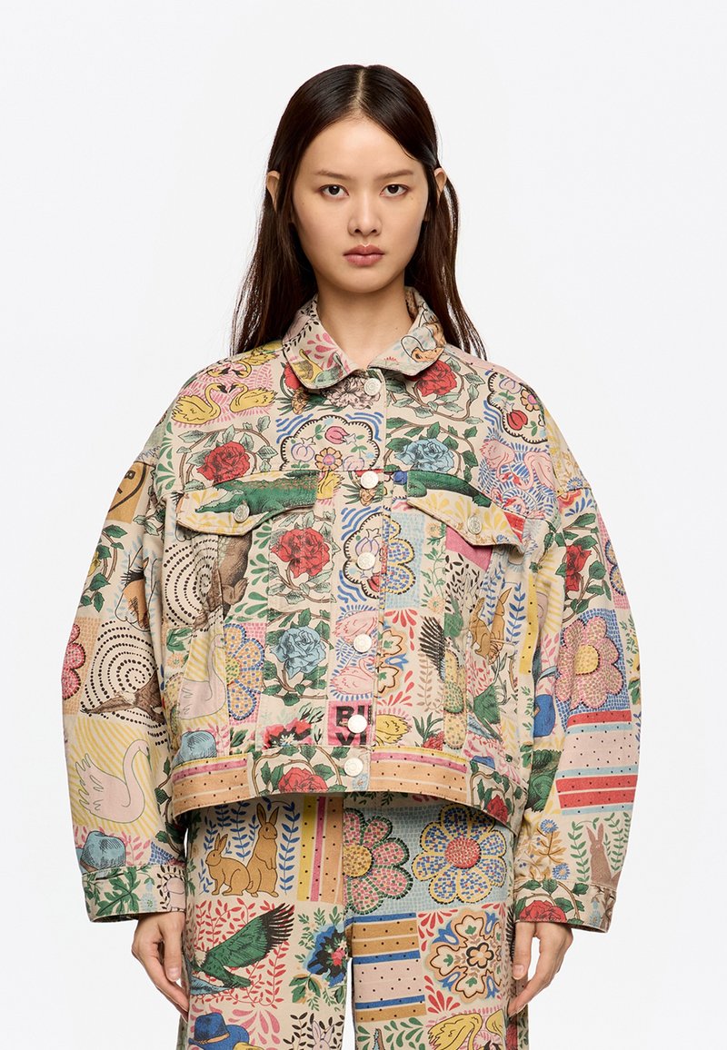 Chaqueta de mezclilla de gran tamaño y multicolor con patrones florales y de animales, dos bolsillos en el pecho y cierre de botón a presión.