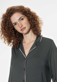 Grijze button-up shirt met contrasterende lichtroze bies, voorzien van een ingesneden kraag en een gladde textuur, geschikt voor relaxed draagcomfort.