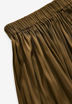 Elastický pás sukne s plisovaním v tmavo olivovej farbe. Textúra je hladká s vertikálnymi záhybmi, ktoré vytvárajú prúdny dizajn.