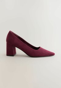 Scarpa con tacco alto in suede bordeaux, con punta affilata e tacco largo e quadrato. Texture liscia e design minimalista senza hardware visibile.