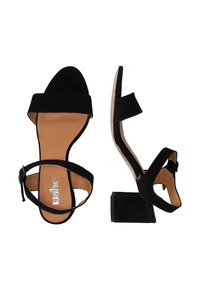 Sandali neri in suede con tacco spesso, punta aperta e cinturino alla caviglia con fibbia. La soletta è marrone chiaro, con il marchio ben visibile.