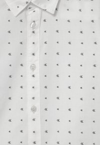 Witte shirt met een fijn geruit patroon, voorzien van kleine zwarte CK-logo's, een klassieke kraag en doorzichtige knopen aan de voorkant.