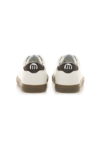Zapatilla blanca con parte superior de cuero suave, acentos marrones en el talón y una sección de plástico transparente. Presenta una suela de goma plana.