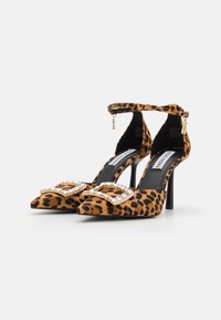 Cipele s leopard uzorkom s oštrim čepom, crnim stileto potpeticama, remenom oko gležnja i ukrasnom kopčom s zlatnim detaljima i prozirnim rhinestones.