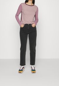 Top s dlouhými rukávy v barevném blokovém provedení v růžové a purpurové barvě, kombinovaný s černými džíny s vysokým pasem a vícebarevnými teniskami. Ležérní, volný střih.