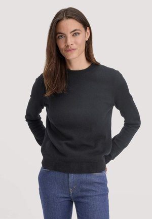 Black, ribbed crew-neck sweater in a soft knit fabric, featuring long sleeves and a fitted waistband, paired with blue jeans.
