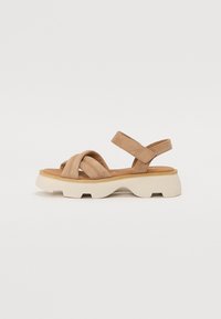 Tan faux suede sandals with crossed straps, a cushioned footbed, and a chunky white platform sole featuring groove details.