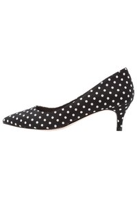 Black pointed-toe women’s kitten heel shoe with white polka dots and low slender heel on white background.