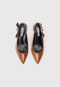 Καφέ λουστρίνι ψηλοτάκουνα μπαλαρίνες με μαύρες σόλες και διακοσμητικές κορδέλες που διαθέτουν το λογότυπο KARL LAGERFELD σε λευκές θηλές αστραγάλου.