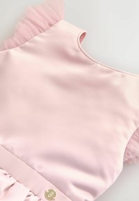 Rozā satīna kleita ar tilla volānu uz pleca un zelta pogu detaļu jostas vietā. Gluda tekstūra un apaļa kakla izgriezums.