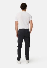 Black cotton trousers with a straight leg, paired with a white short-sleeve shirt and white sneakers. Back view, no patterns or accents.