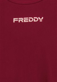 Maglietta maroon; maniche corte; morbido cotone; presenta il logo bianco "FREDDY" stampato centralmente in un carattere audace e moderno.