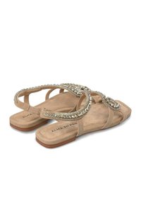 Beige Flachsandalen mit verzierten Riemen, die mit Strasssteinen besetzt sind, aus weichem Wildleder und einer flachen Gummisohle. Markenname auf der Innensohle gedruckt.
