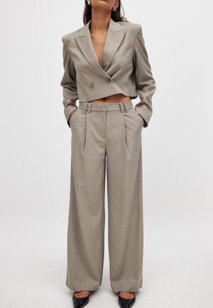 Blazer court gris clair à double boutons et pantalon à jambe large, avec un devant plat, des poches latérales et une texture de tissu lisse.