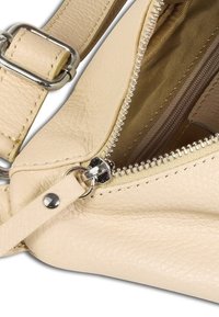 Beige lederen handtas met een gestructureerd oppervlak, voorzien van zilverkleurige hardware, een ritssluiting en een nylon gevoerde binnenkant voor organisatie.