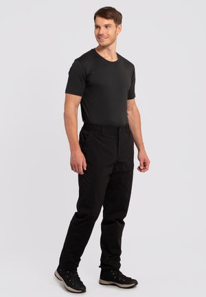Zwarte short-sleeve t-shirt gecombineerd met zwarte broek, met een losse pasvorm en elastische tailleband, gedragen met zwarte wandelschoenen.