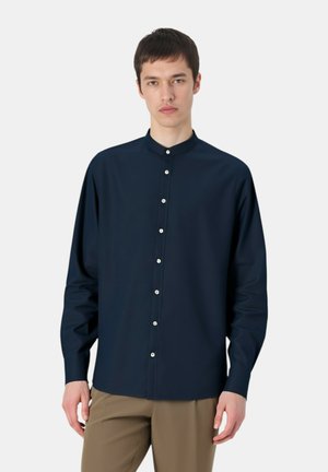 Camicia a maniche lunghe blu navy con colletto alla cinese, caratterizzata da chiusura con bottoni e tessuto liscio. Silhouette aderente, design minimalista.