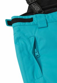 Turkusowe spodnie narciarskie posiadają boczną kieszeń na zamek, regulowany pas z zapięciem na rzep oraz trwałą, gładką tkaninę.