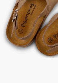 Brown leather sandals with a cross-strap design, featuring a metal buckle and a soft textured insole. Label shows "Pisamonas, Hecho en España".