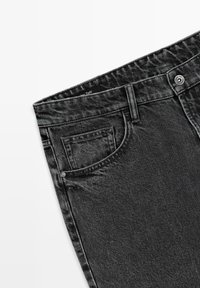 Black denim jeans folded, showing top waist area with front pocket, belt loop, and metal button with brand engraving.