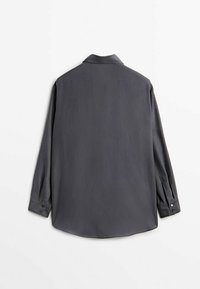 Chemise gris foncé à manches longues avec boutons et poignets, vue de dos sur un fond blanc uni.